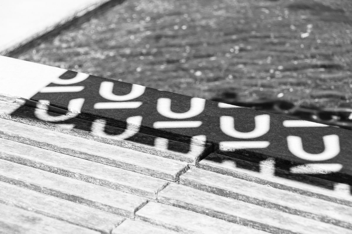 Black and white close-up of Nuans branded cards with repeating logo letters on a wooden surface, abstract brand detail shot