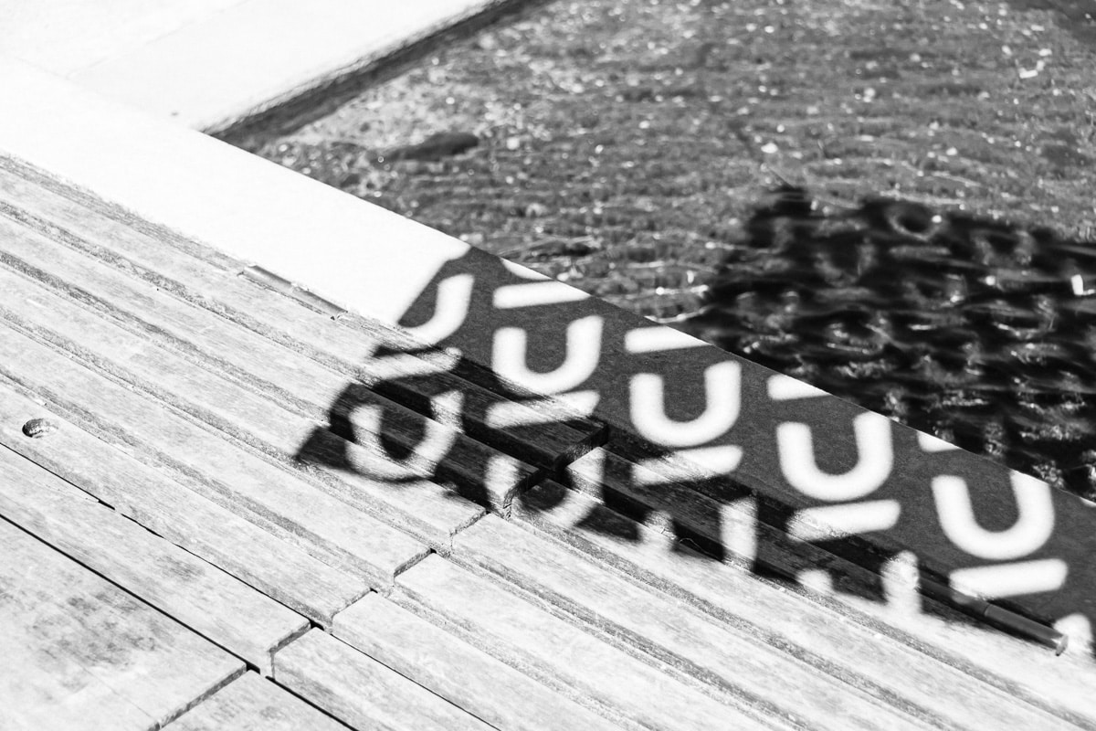 Black and white abstract photo of Nuans branding reflected on a wooden dock surface near water, corporate law firm visual ide