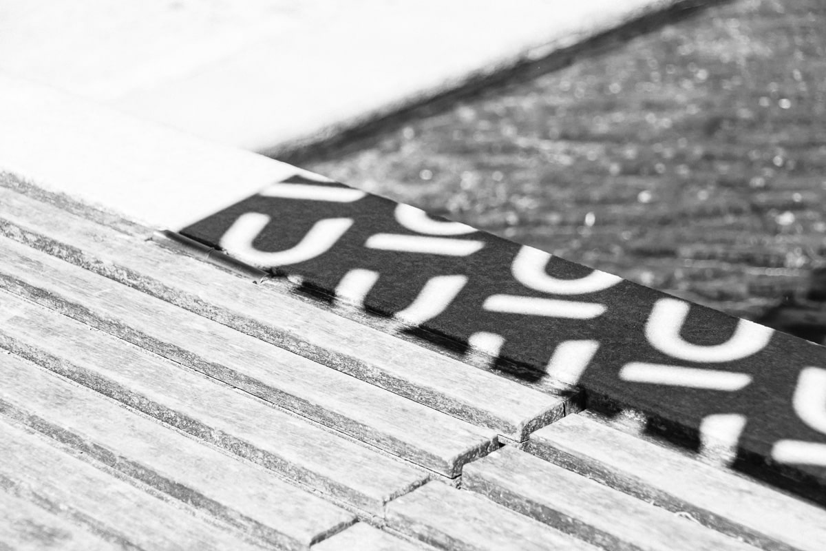 Close-up of a wooden deck with a bold black and white patterned strip, abstract detail from Nuans law firm brand photography