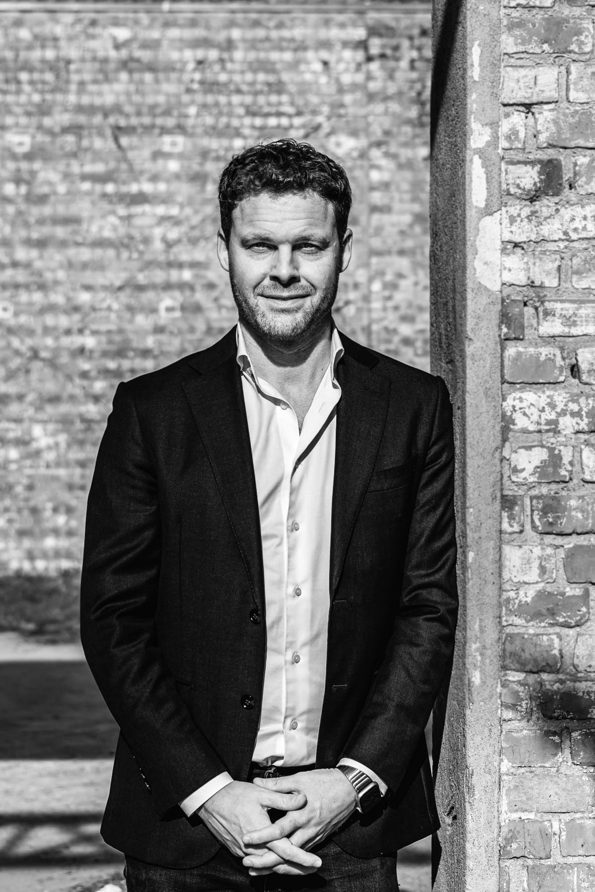 Hannes Abraham, partner at Nuans law firm, in a black and white professional portrait against a brick wall background